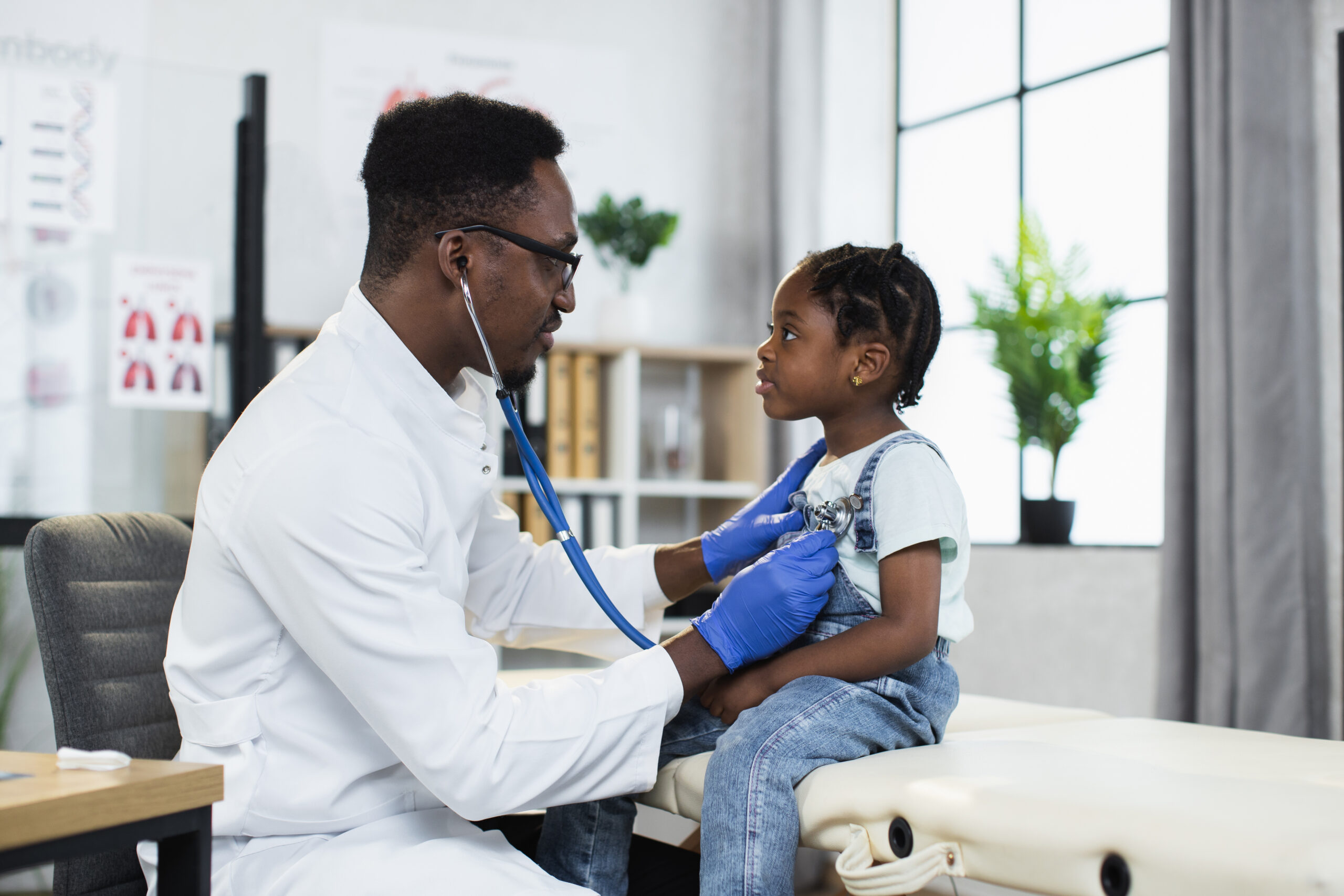 African doctor using stethoscope for listening girl’s lungs